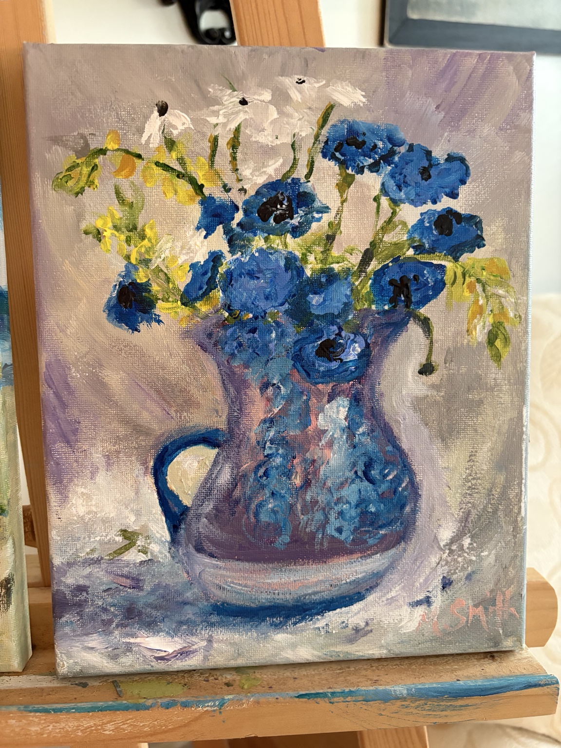 Still life painting of blue, white, and yellow flowers in a blue pitcher