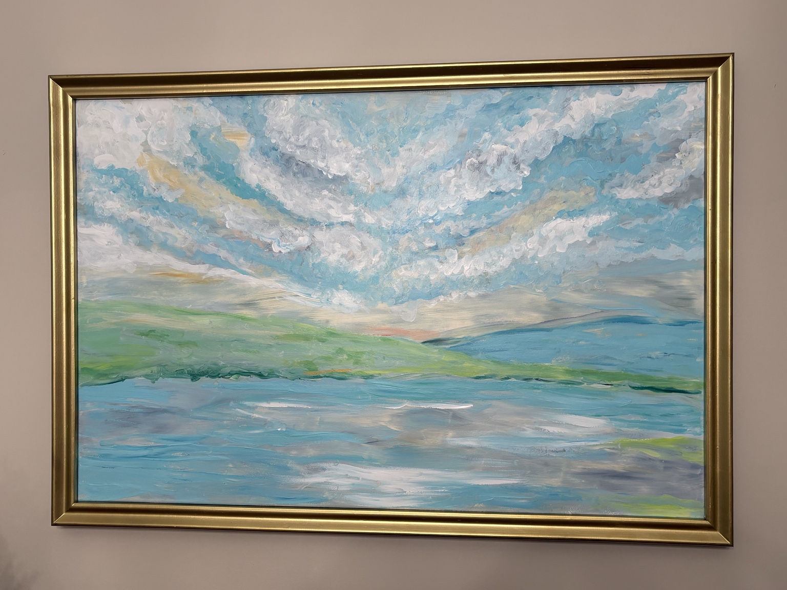 Mary's gold-framed painting of blue water beneath a luminous cloud-filled sky